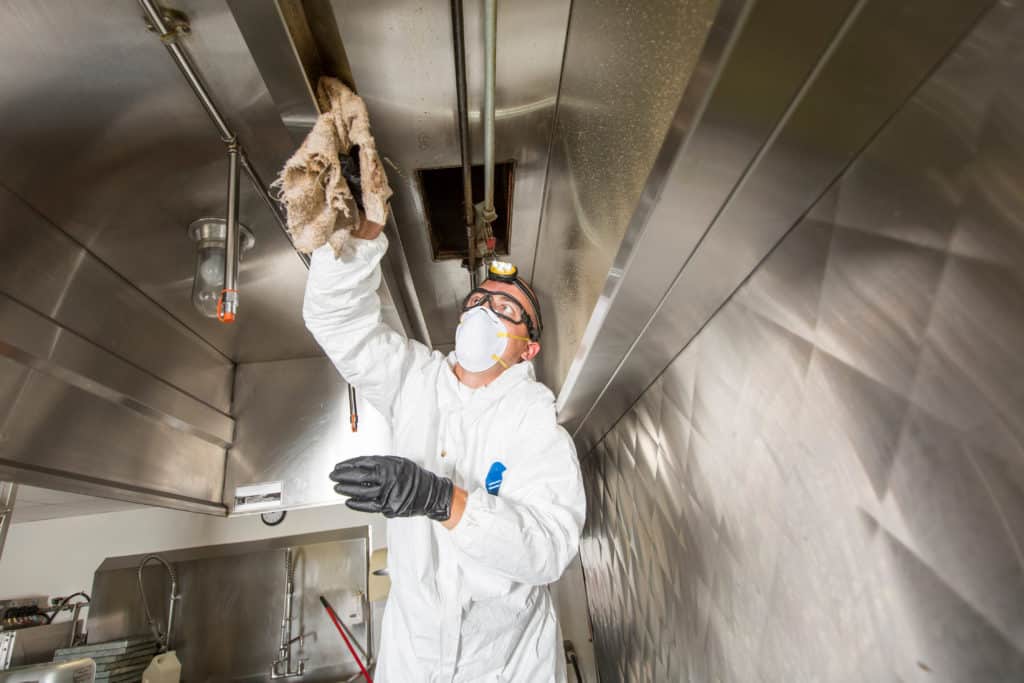 Photo shows a man cleaning a stainless steel industrial area.